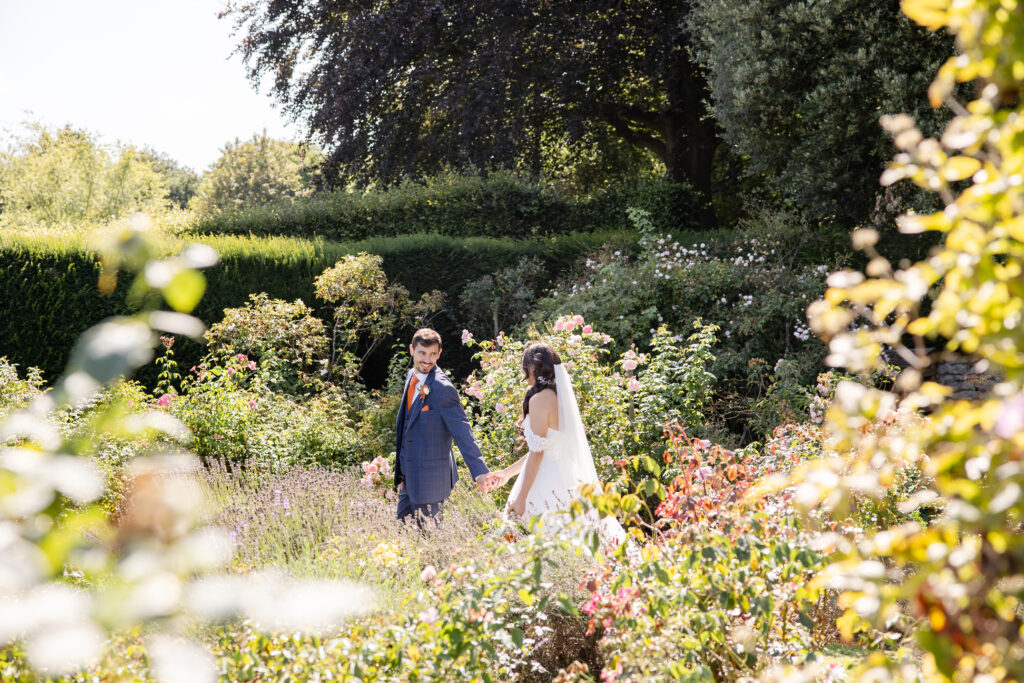 Bride & Groom walking through the gardens at Nettlestead Place
